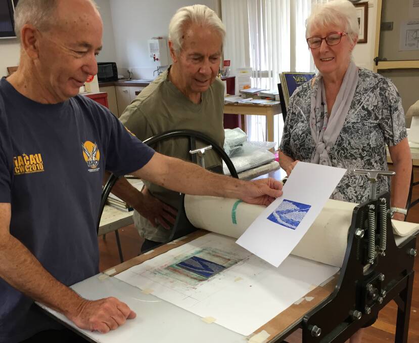 PRINT: Yurara Printmaker Tutor Cliff Eames shows Robin Wilson and Gloria Dietz-Kiebron an example of one of the lino cut prints that visitors to the Printmaking Exhibition can make from February 22.
