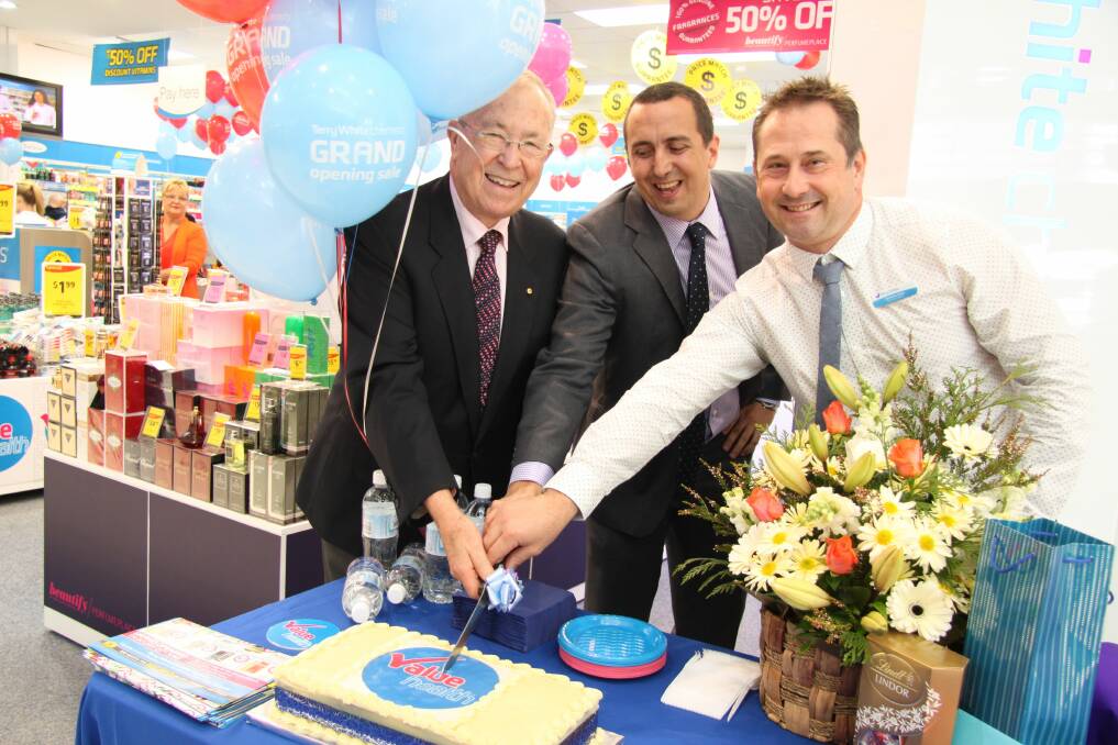 Terry White (left) cuts the cake at the opening of the recently refurbished Terry White Chemists Capalaba with Capalaba MP Don Brown (centre) and Terry White Chemists Capalaba owner Brendon Reck.