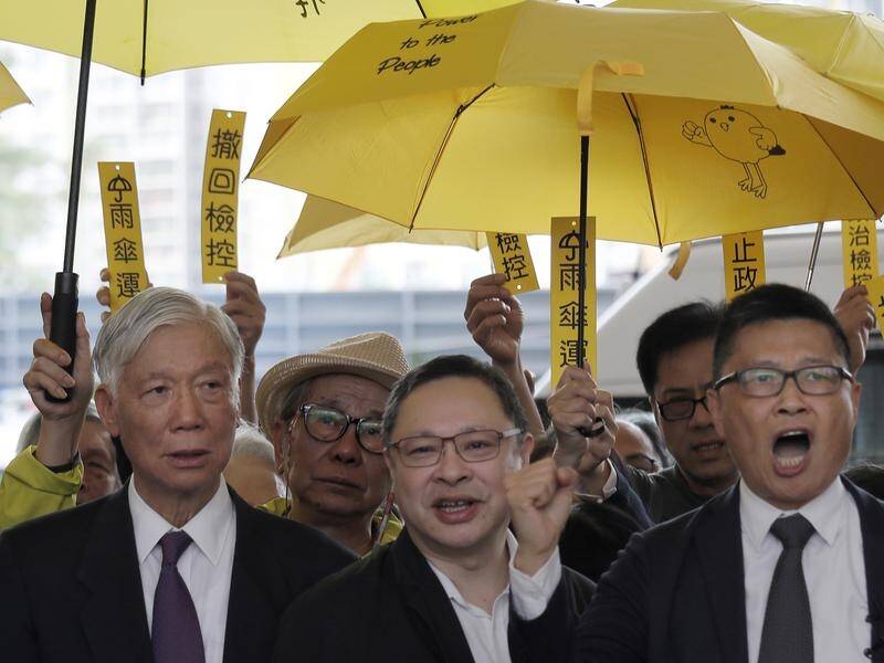 Pro-democracy activists shout slogans before entering a Hong Kong court for their trials.