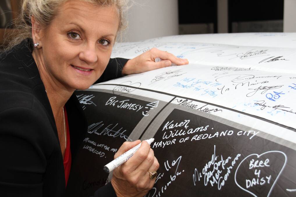 Mayor Karen Williams signs the Fatality Free Friday inflatable car at Redland City Council.Phot by Chris McCormack