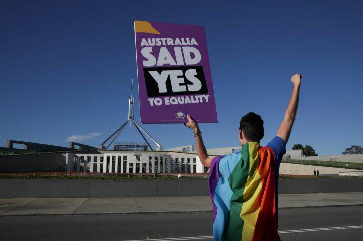 Supporters of same-sex marriage pose for photographers with the rainbow flag during a rally on the front lawn of Parliament House ahead of the vote on the Marriage Amendment Bill, at Parliament House. Photo: Alex Ellinghausen