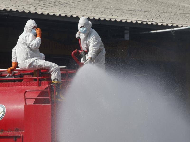 Thai workers spray disinfectant at a shrimp market in Samut Sakhon where a virus outbreak occurred.