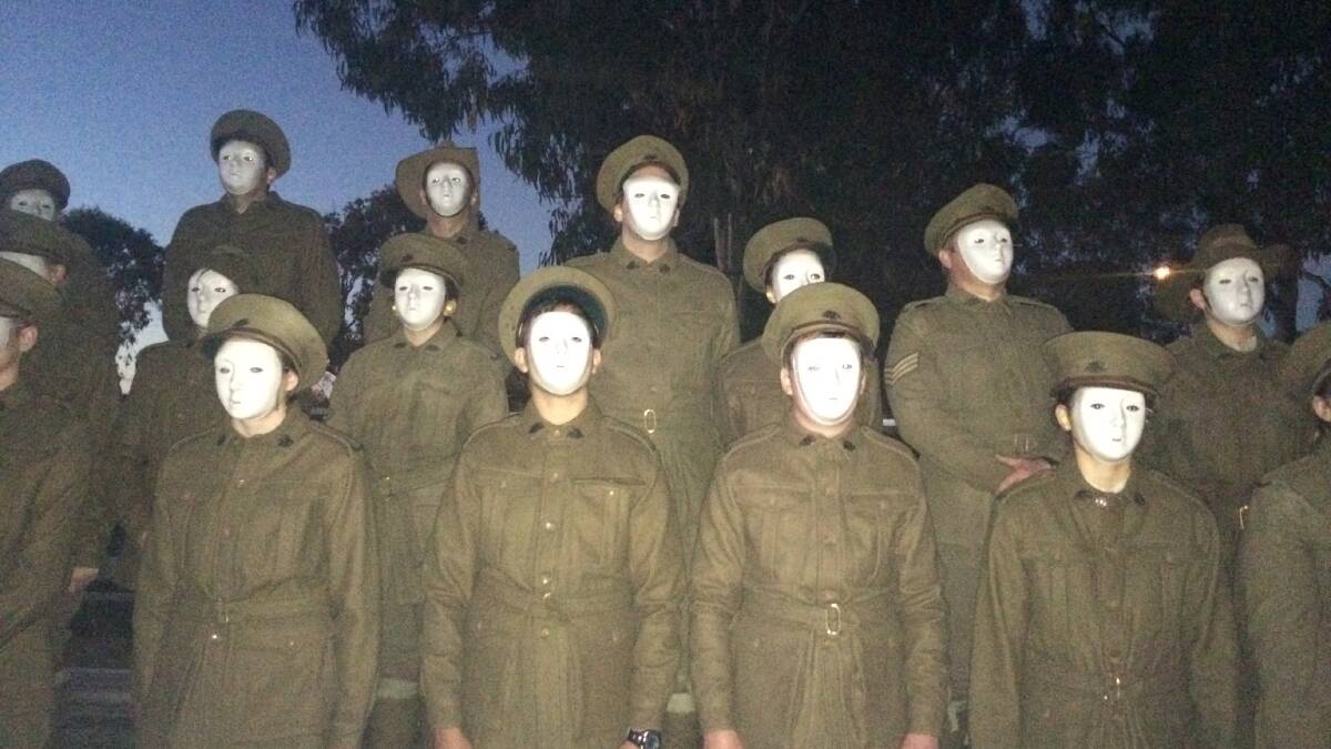 Eighteen Mount Cotton Scout members dressed as faceless soldiers placed roses at the Redland Bay cenotaph after a rousing recorded re-enactment of the landing at Gallipoli during the Dawn Service at Redland Bay. PHOTO: JUDITH KERR 