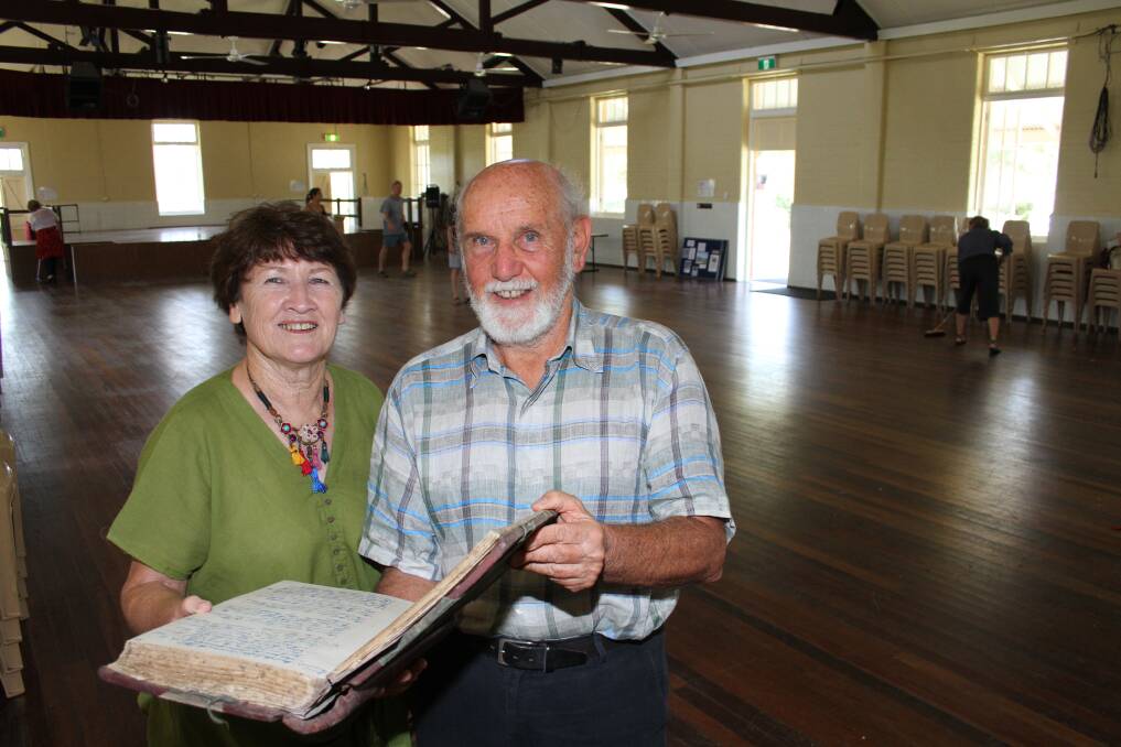 Julie Hislop, from North Stradbroke Island Historical Museum, and Howard Gill look through an old book of minutes at the hall.