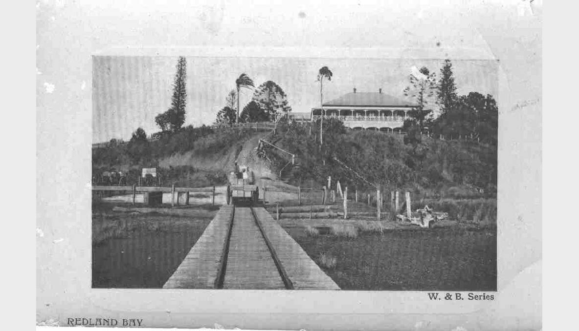 The Redland Bay Hotel and the jetty below it in the early 1920s. This jetty was the main one used by farmers from 1898 to 1909. The two tracks on the jetty were for a trolley that carried the fruit and vegetables to the boats. The boats took the produce to market in Brisbane.